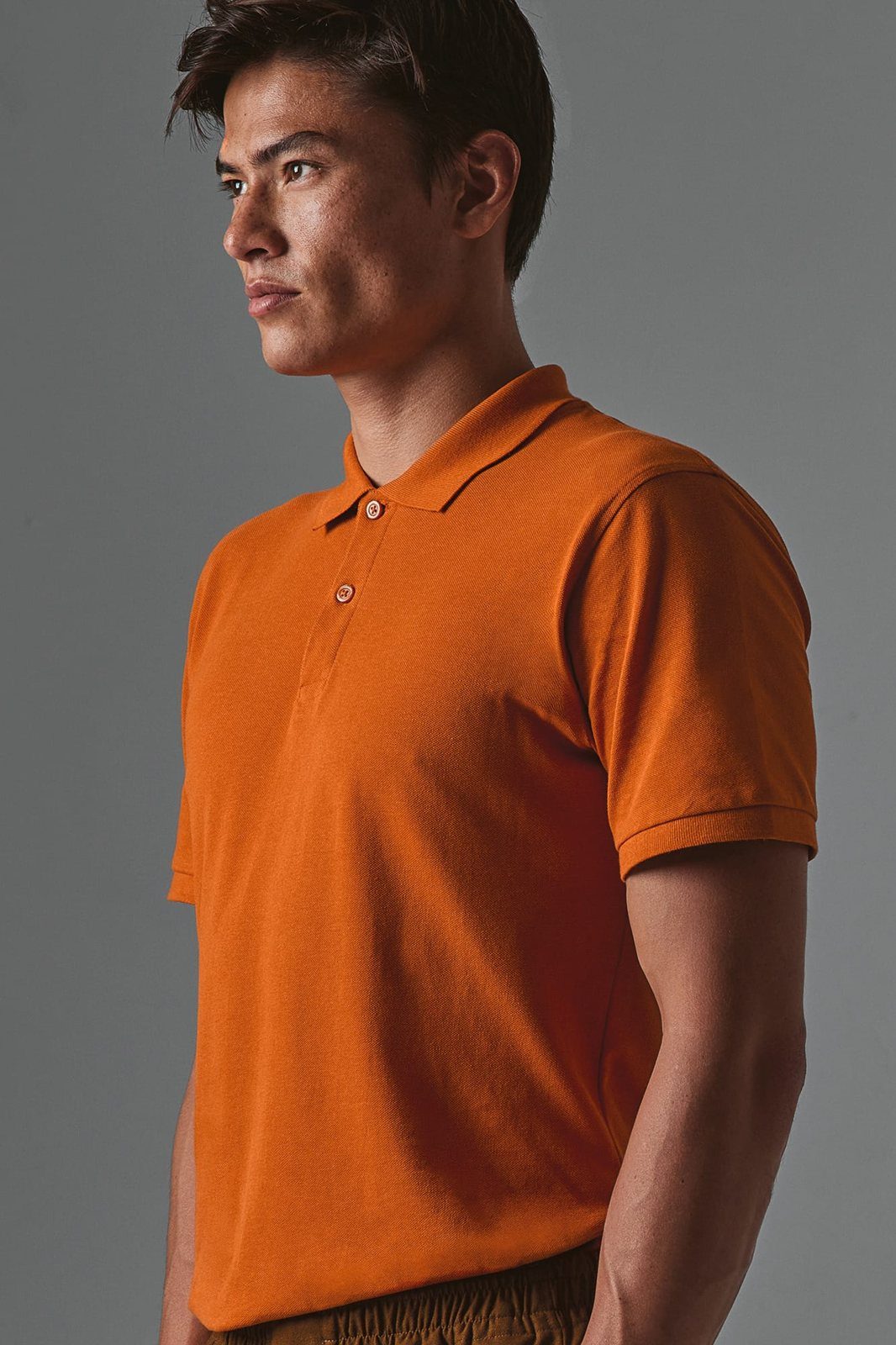 Man in een oranje polo, van opzij gefotografeerd