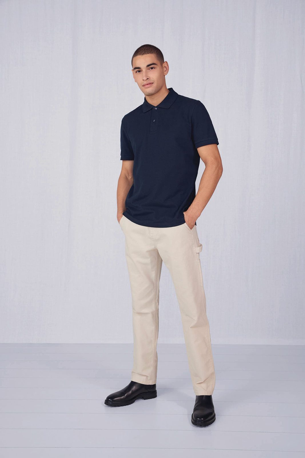 Man in een donkerblauwe polo en een crèmekleurige broek