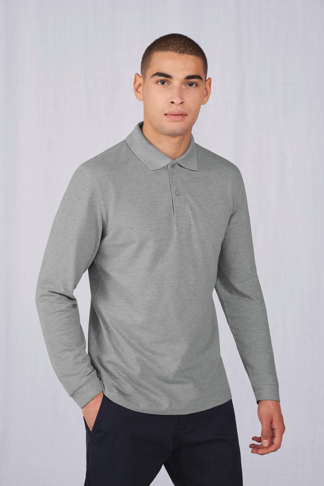 Man in een grijze polo met lange mouwen en een donkerblauwe broek