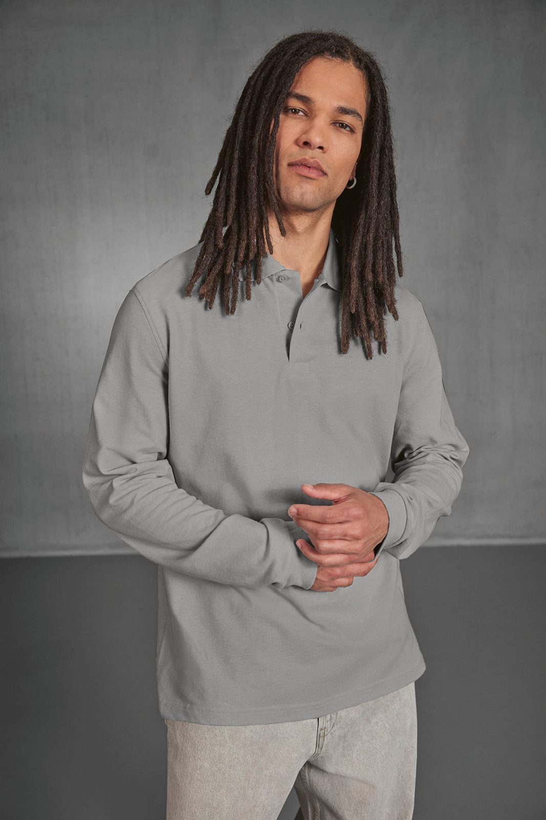 Man met lange dreadlocks in een lichtgrijze polo met lange mouwen