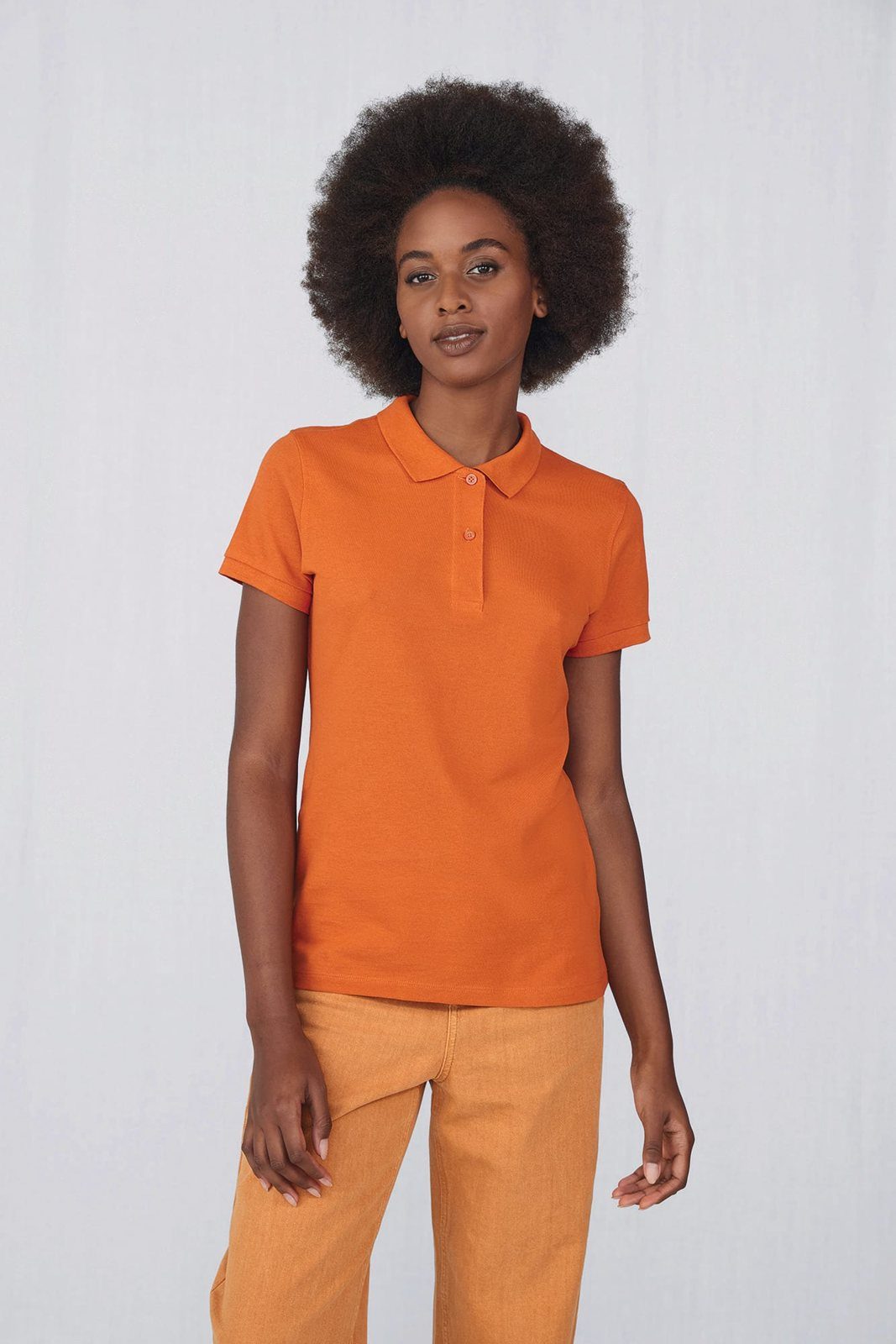 Vrouw met afrokapsel in een oranje damespolo