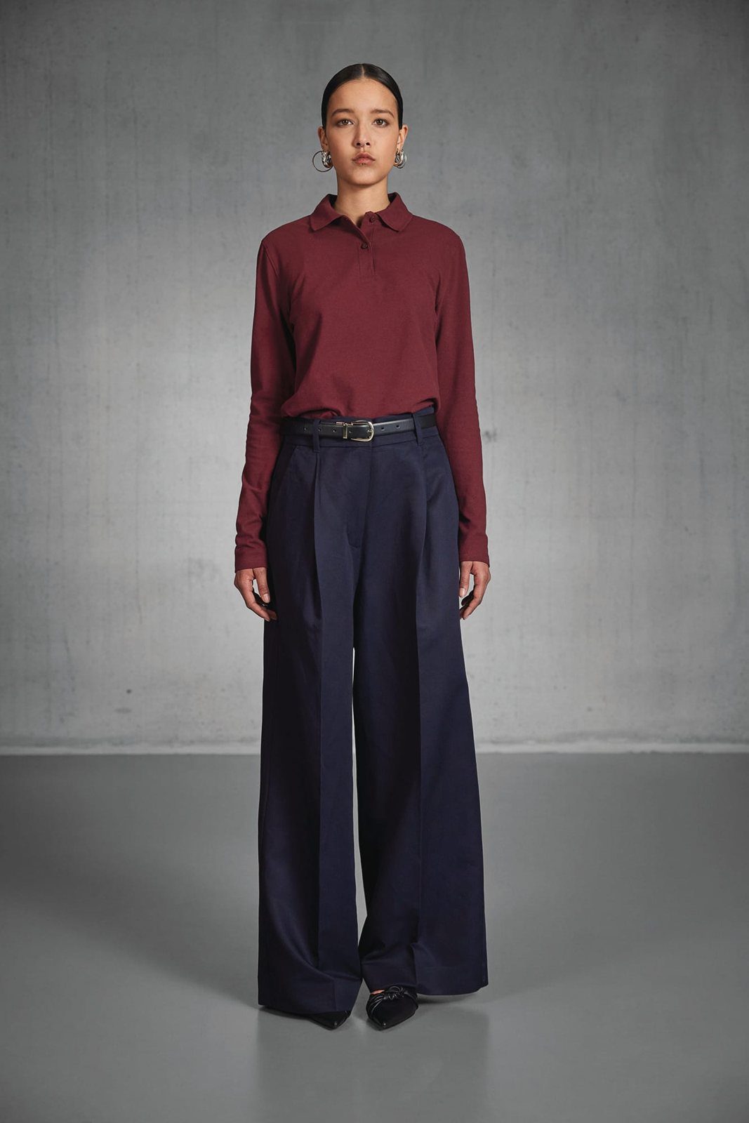 Vrouw in een bordeauxrode polo met lange mouwen en een wijde pantalon
