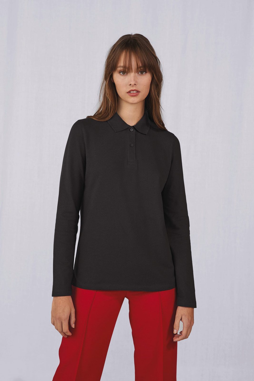 Vrouw in een zwarte polo met lange mouwen en een rode broek