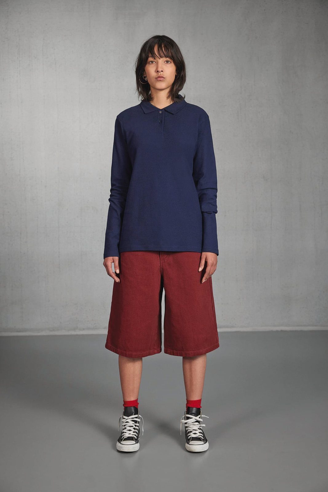 Vrouw in een donkerblauwe polo met lange mouwen en een rode korte broek