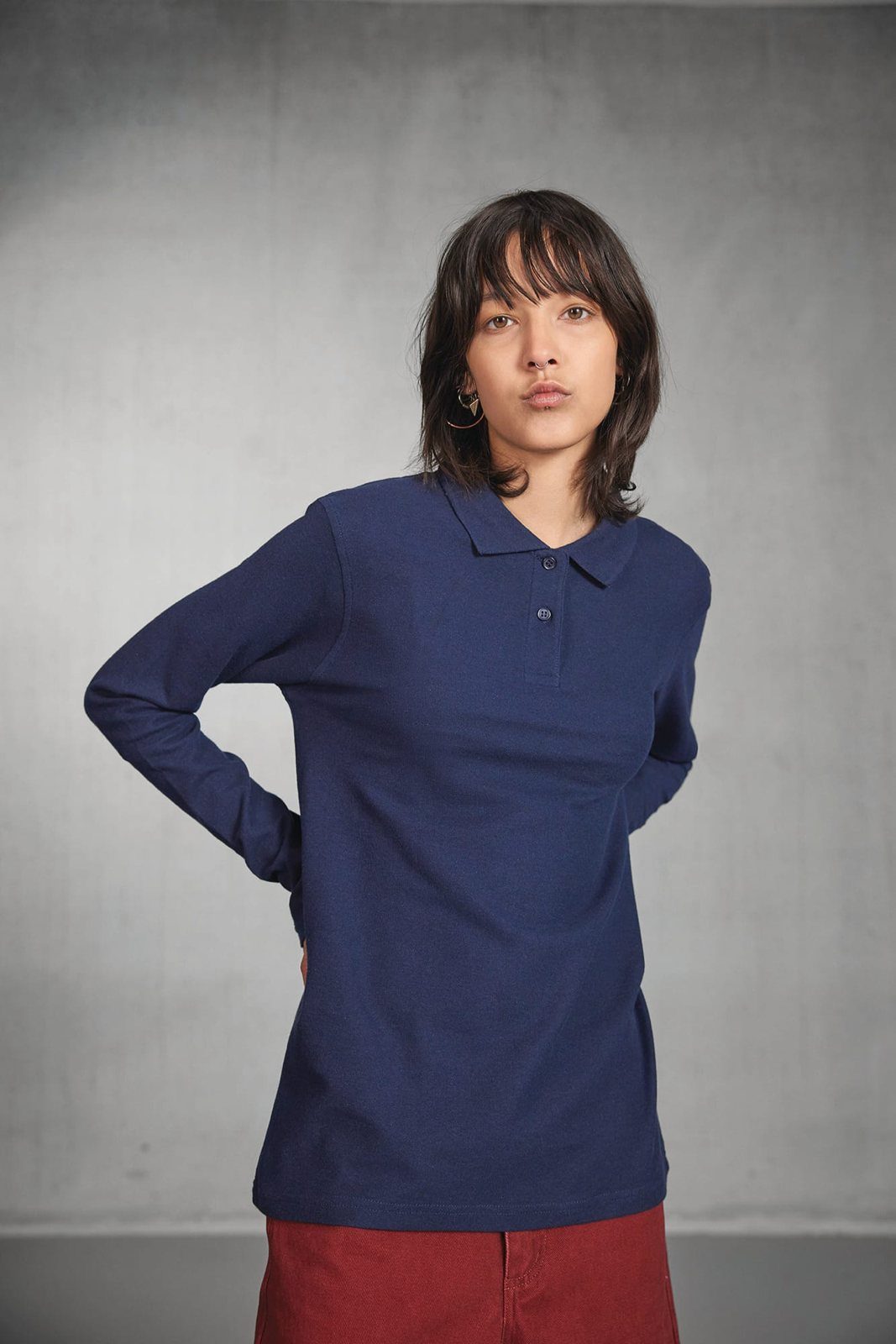 Vrouw in een donkerblauwe polo met lange mouwen, hand in de zij