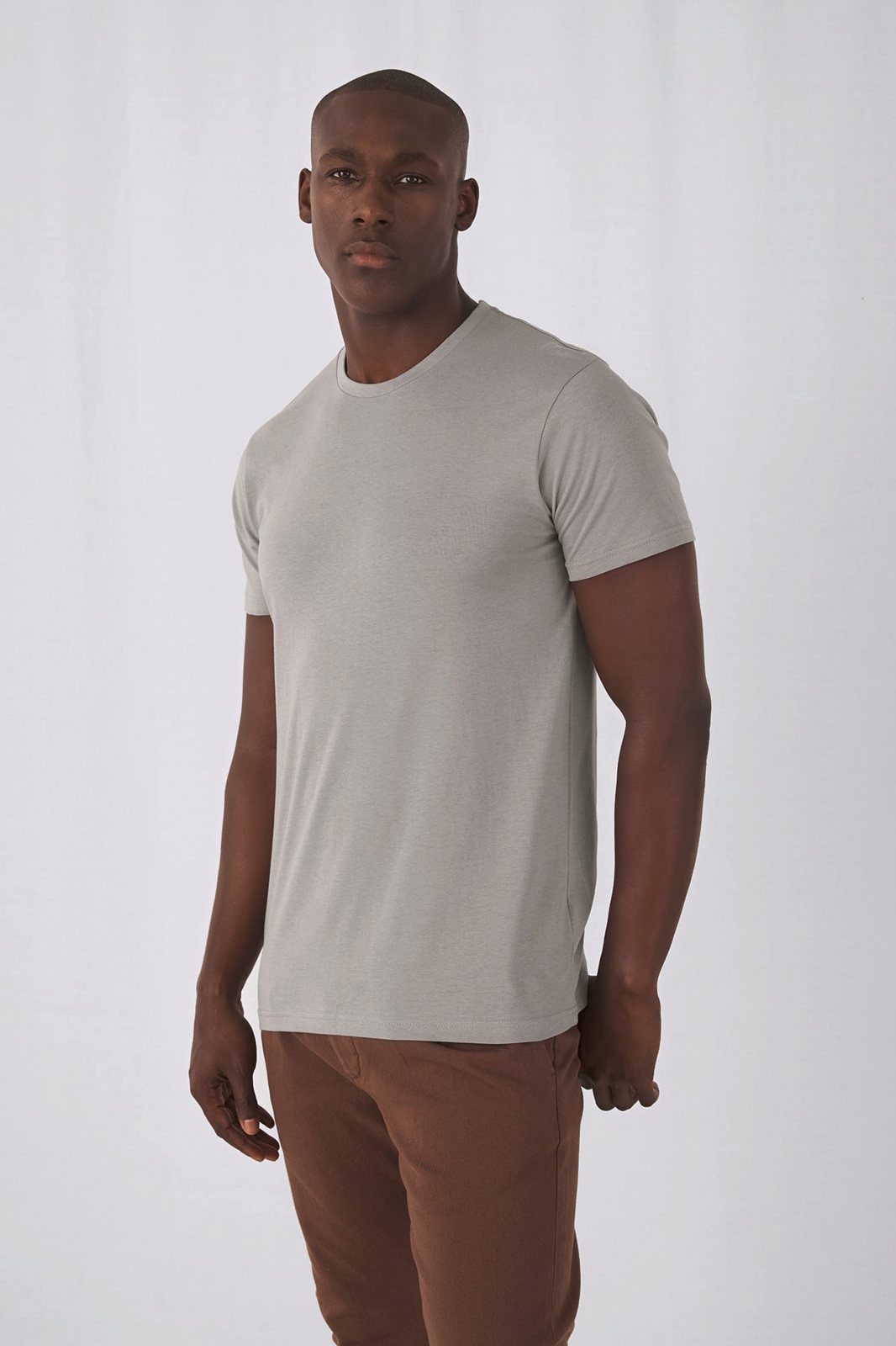 Man in een lichtgrijs T-shirt en een bruine broek