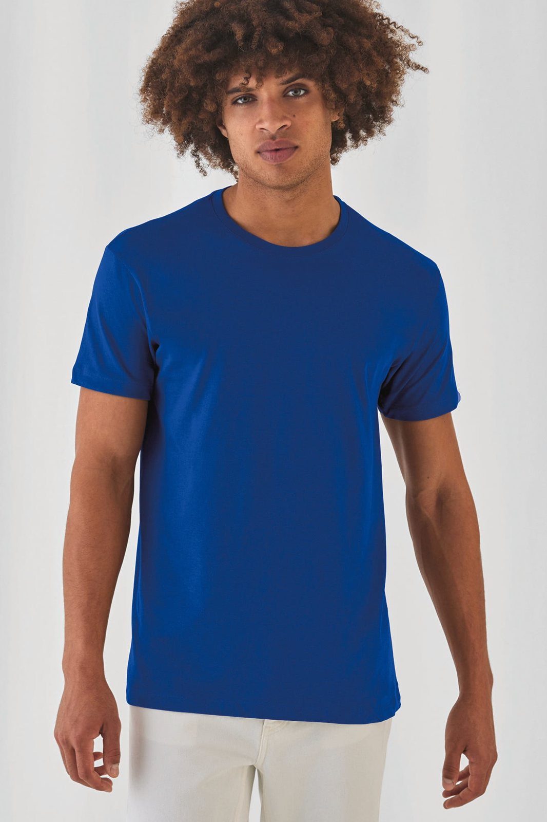Jongeman met grote krullen in een kobaltblauw T-shirt