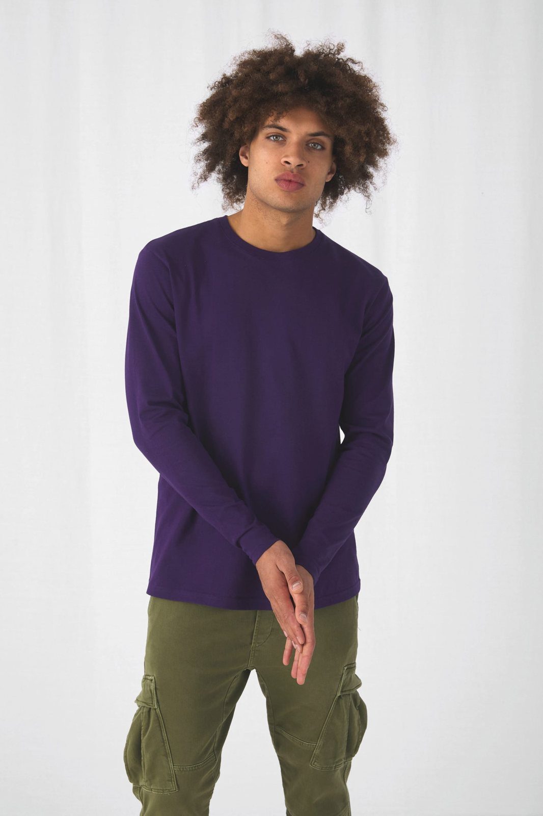 Jongeman met grote krullen in een paars shirt met lange mouwen en een groene cargobroek