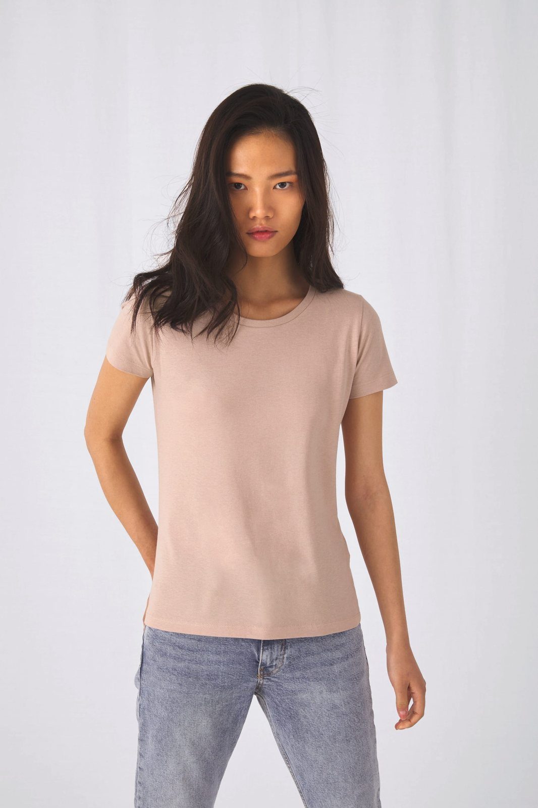 Vrouw met donker haar in een zachtroze T-shirt en een lichte jeans