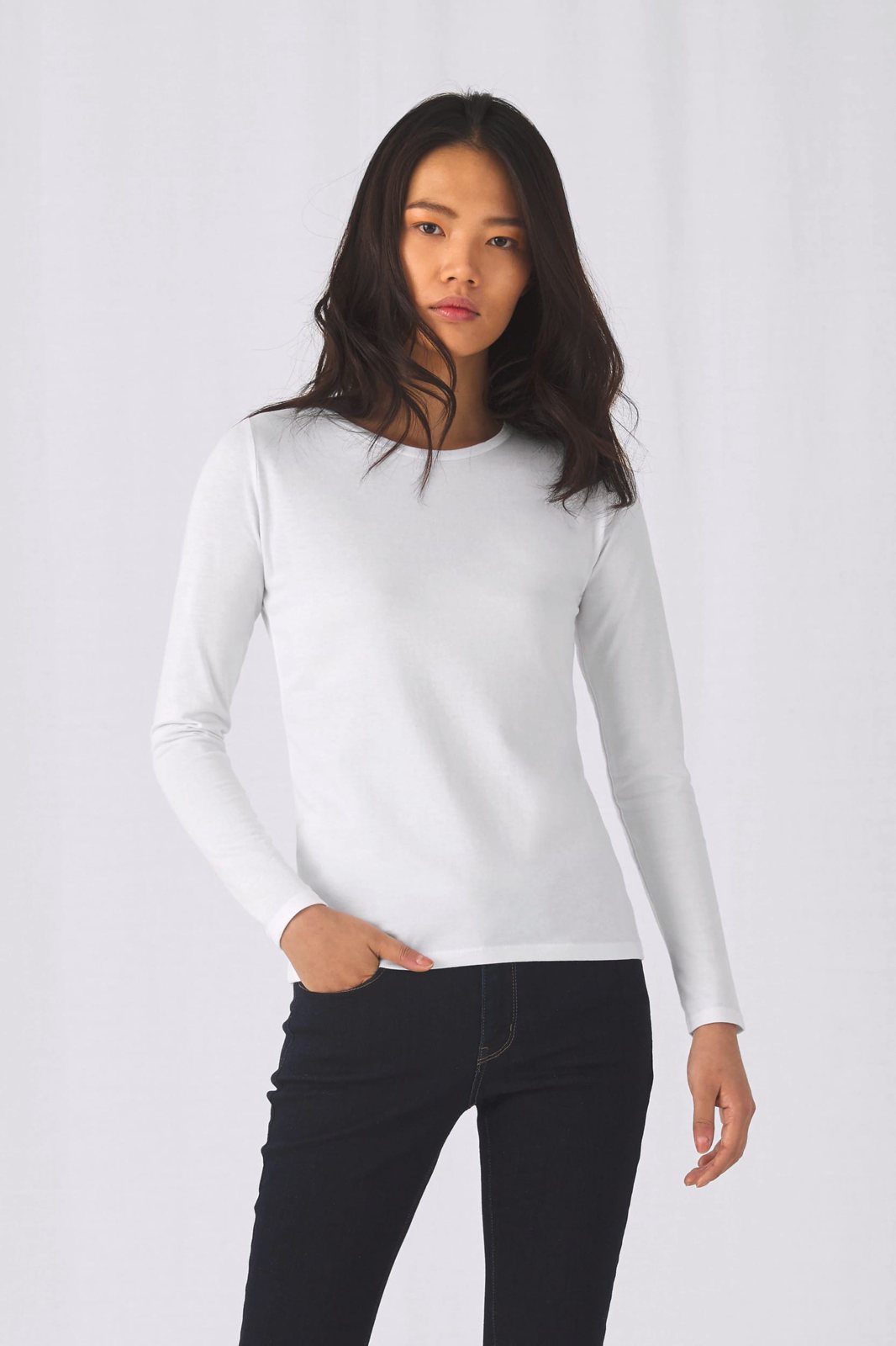 Vrouw met donker haar in een wit shirt met lange mouwen en een donkere jeans