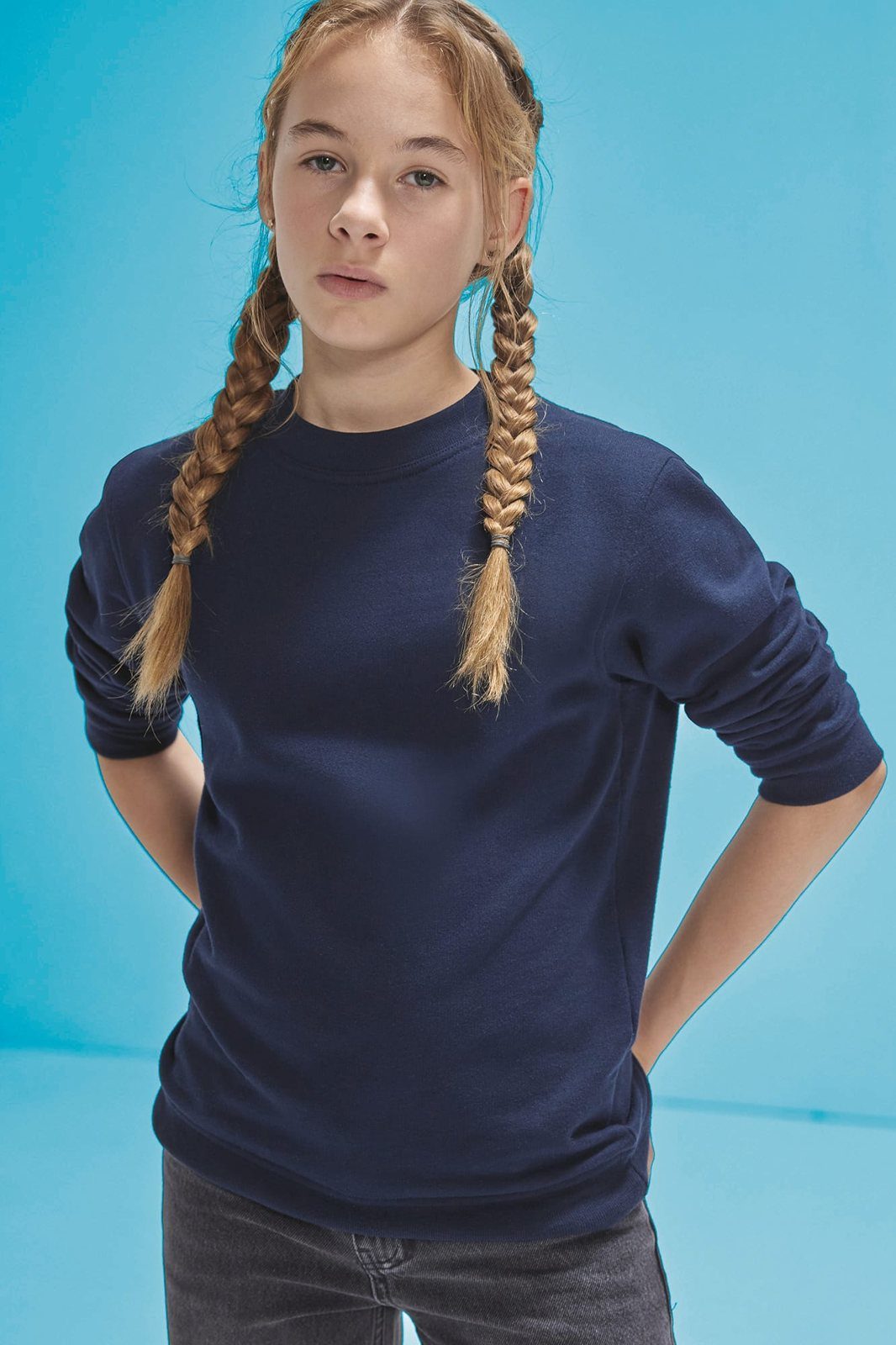 Meisje met lange vlechten in een donkerblauwe sweater met ronde hals