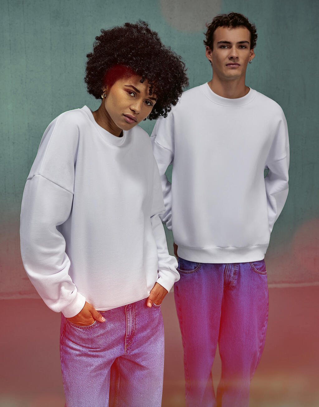 Twee mensen in een witte sweater met ronde hals voor een kleurrijke muur