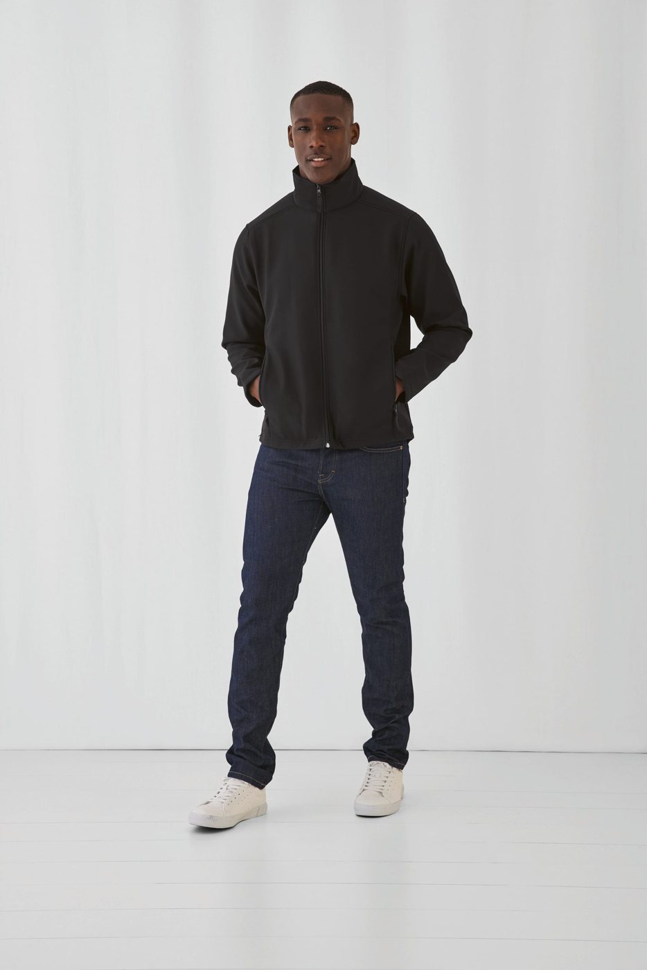 Man in een zwarte softshell jas en een jeans