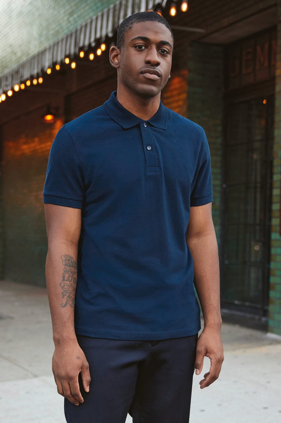 Man in een navy polo voor een café