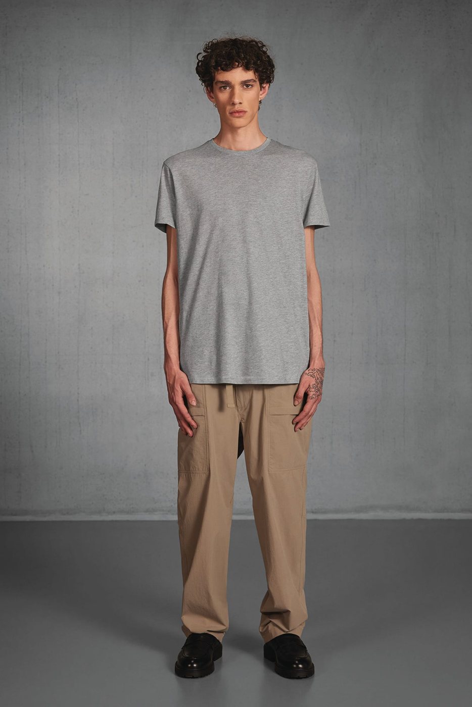 Man in een grijs gemêleerd T-shirt en een beige broek