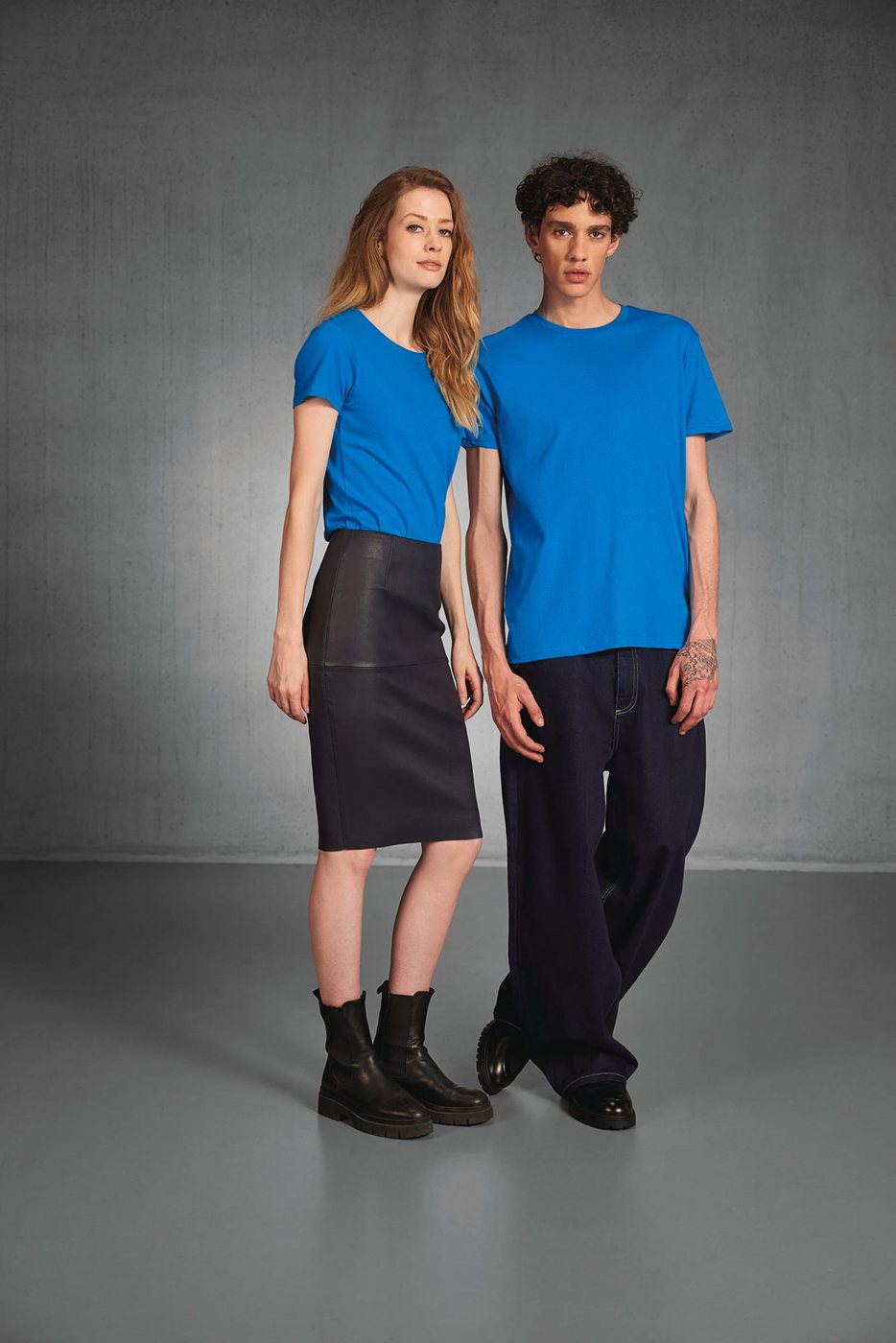 Vrouw en man in hetzelfde blauwe T-shirt in een grijze studio