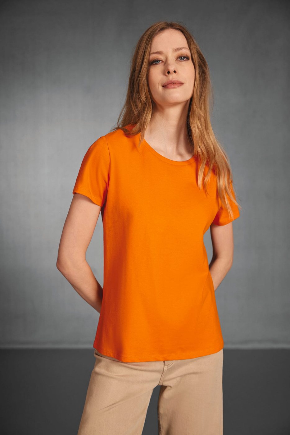 Vrouw in een oranje T-shirt en een beige broek