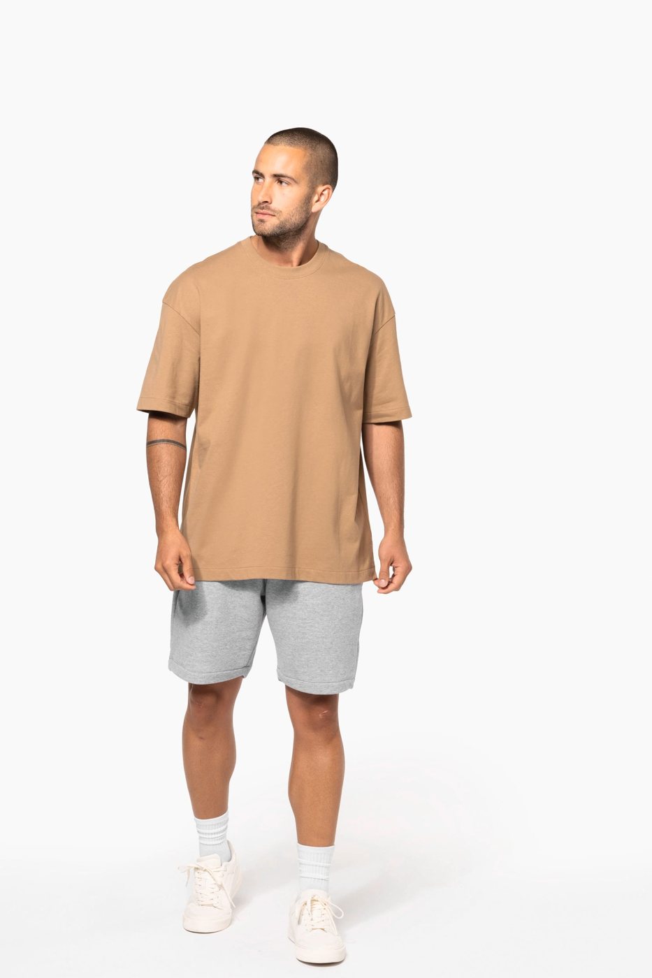 Man in a camel-coloured oversized T-shirt and grey shorts