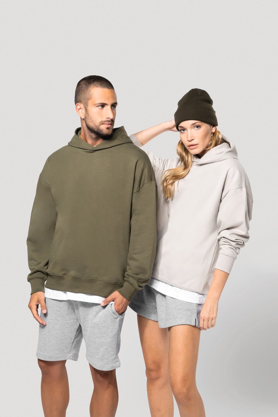 Man in een olijfgroene en vrouw met muts in een lichtgrijze oversized hoodie