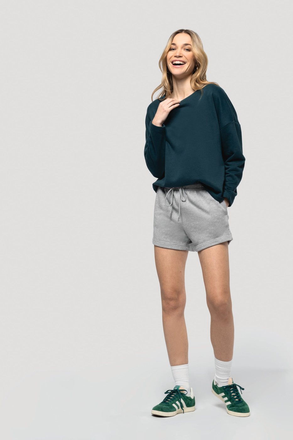 Smiling woman in a dark petrol-coloured roomy sweater and grey shorts