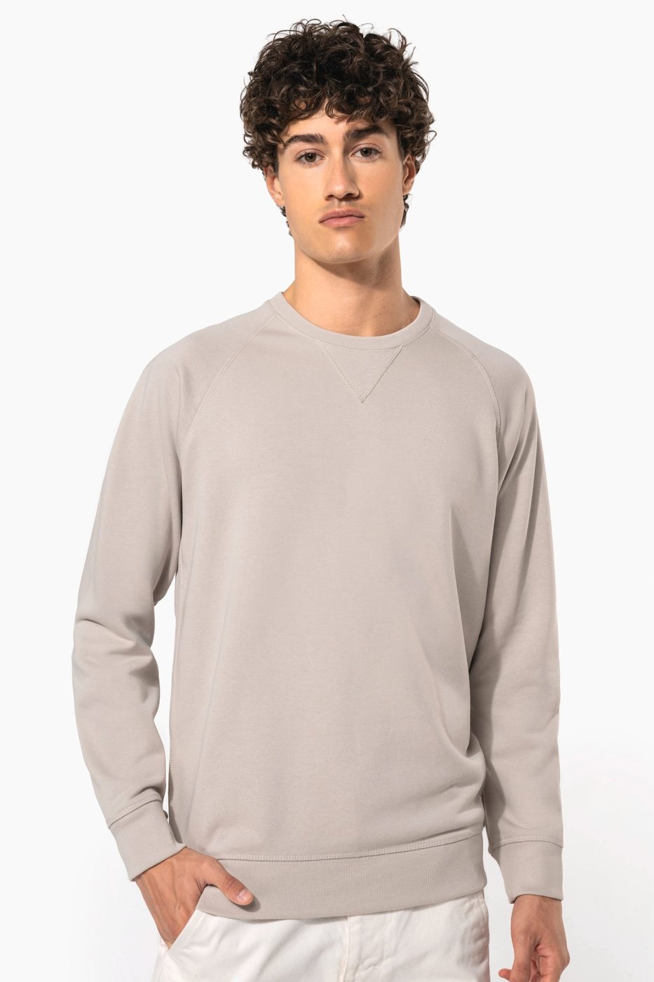 Man met krullen in een lichtgrijze sweater met raglanmouwen