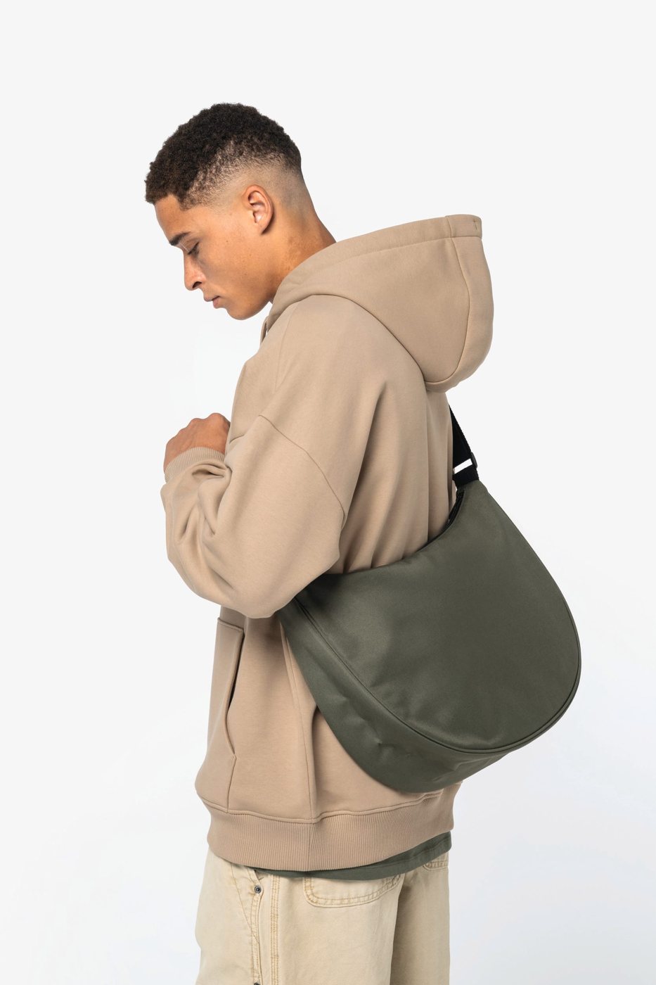 Man in a sand-coloured hoodie with an olive green half-moon bag