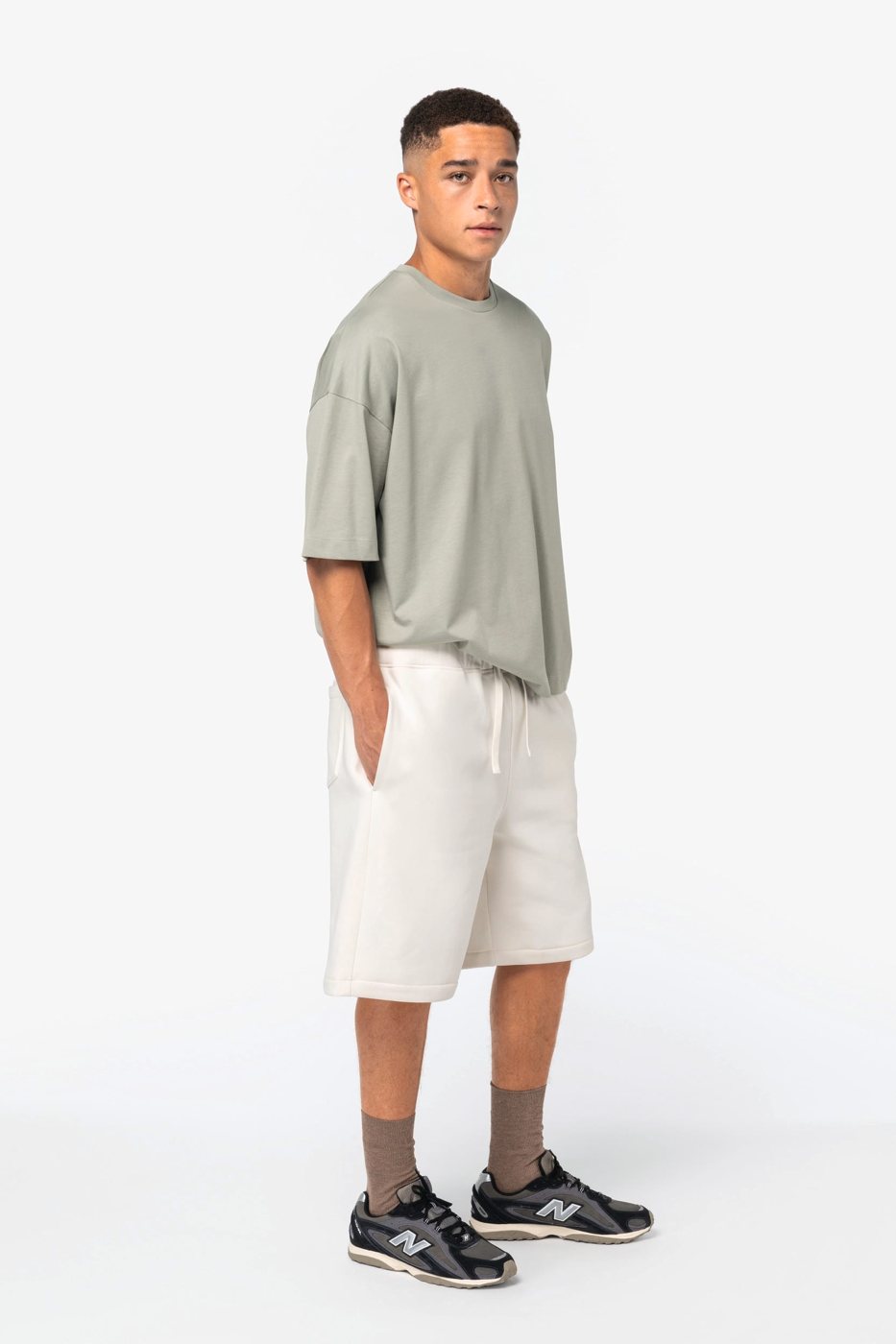 Man in off-white Bermuda shorts and a sage green shirt