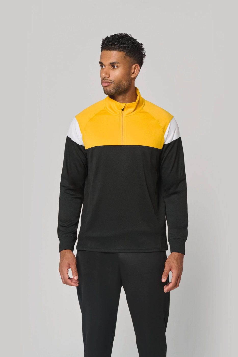 Man in a black training top with yellow shoulders and short zip