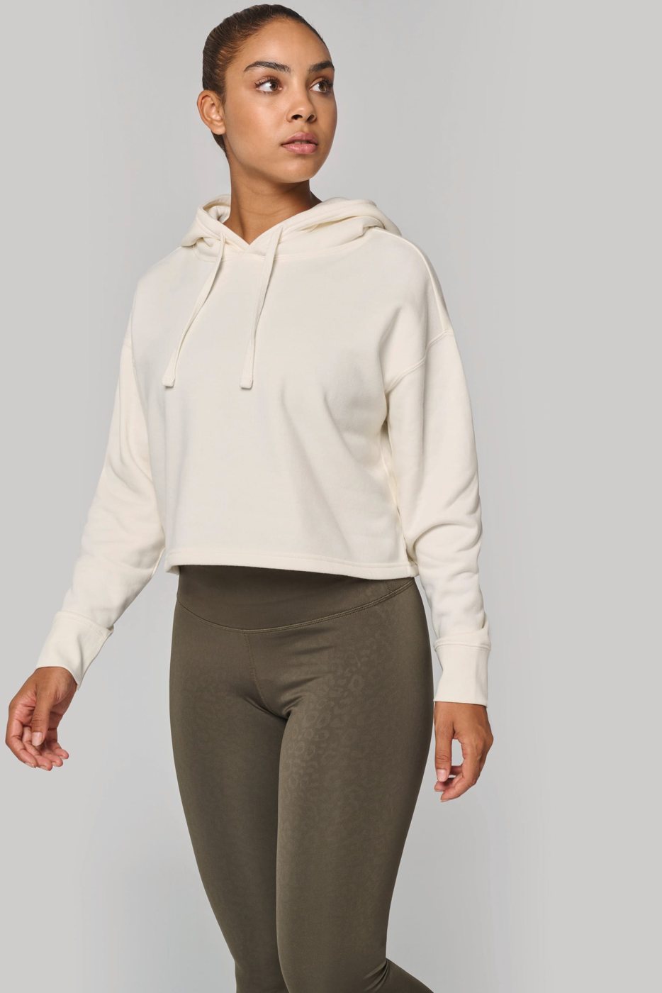 Woman in a cream cropped hoodie and khaki leggings