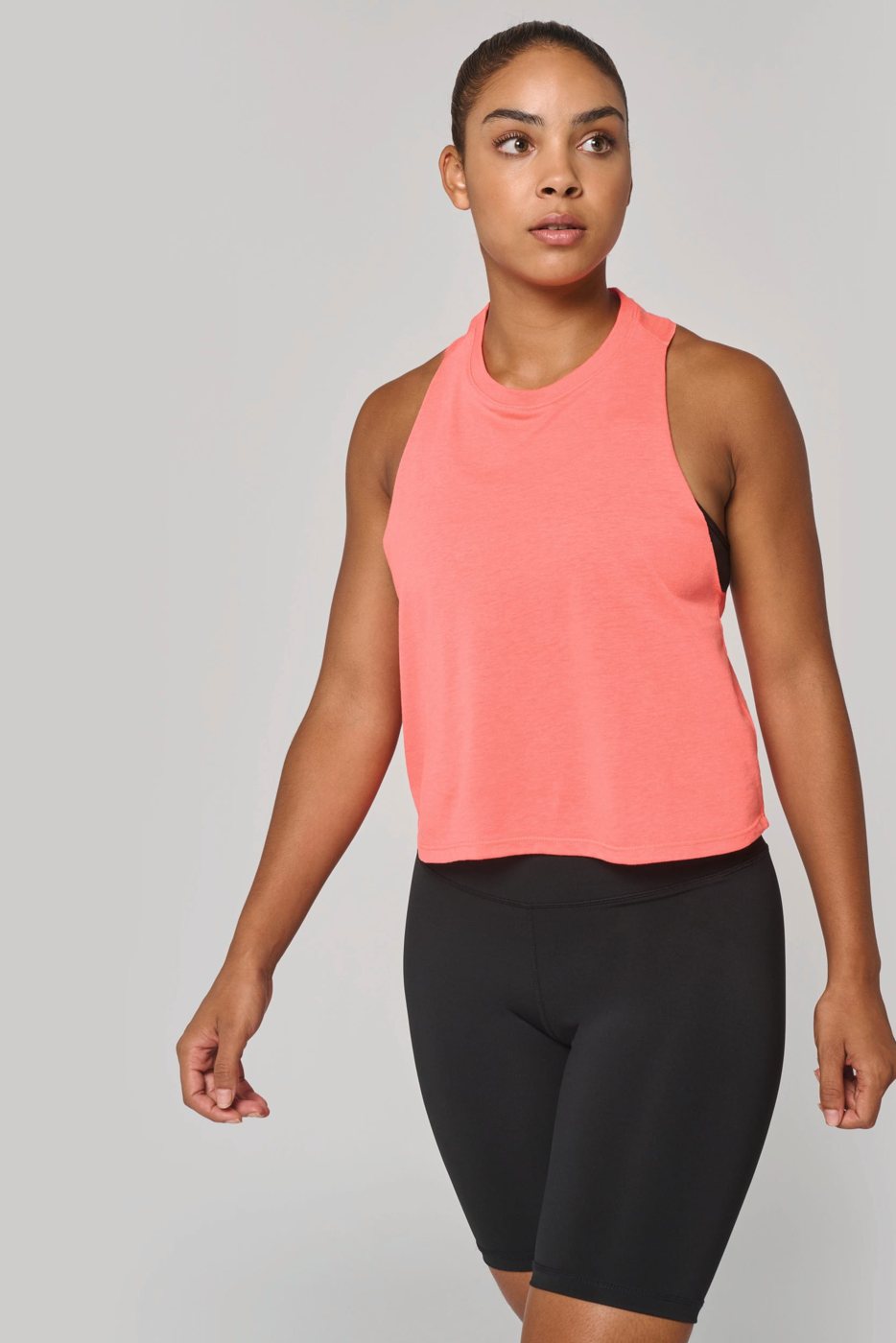 Woman in a coral crop tank top and black sports shorts
