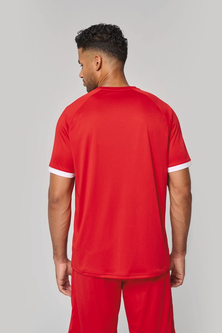 Man in a red sports shirt with white cuffs, seen from behind