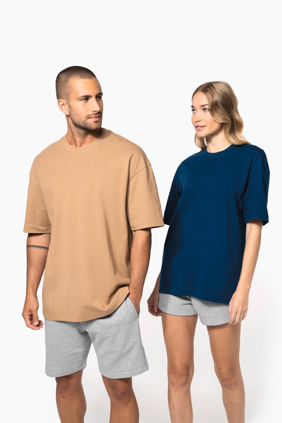 Man in a camel-coloured and woman in a dark blue oversized T-shirt with dropped shoulders