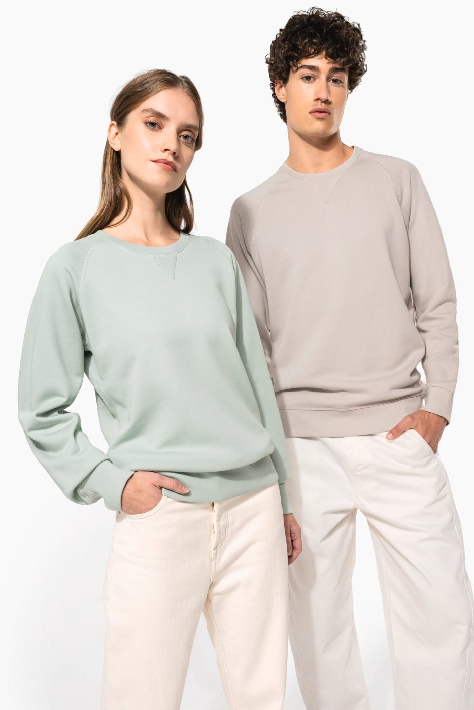 Vrouw in een saliegroene en man in een lichtgrijze biologische sweater met raglanmouwen