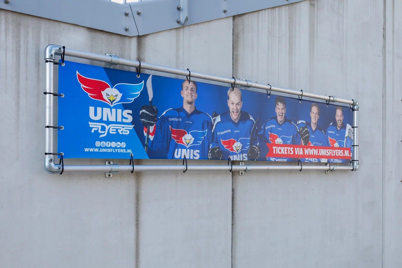Spandoek met sporters aan de gevel van een sporthal