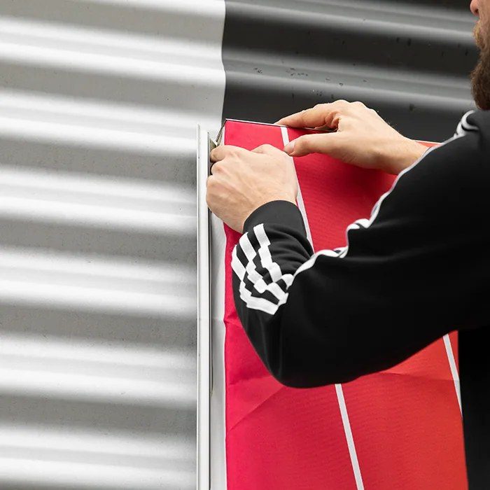 Iemand spant een bedrukt doek in een aluminium buitenframe