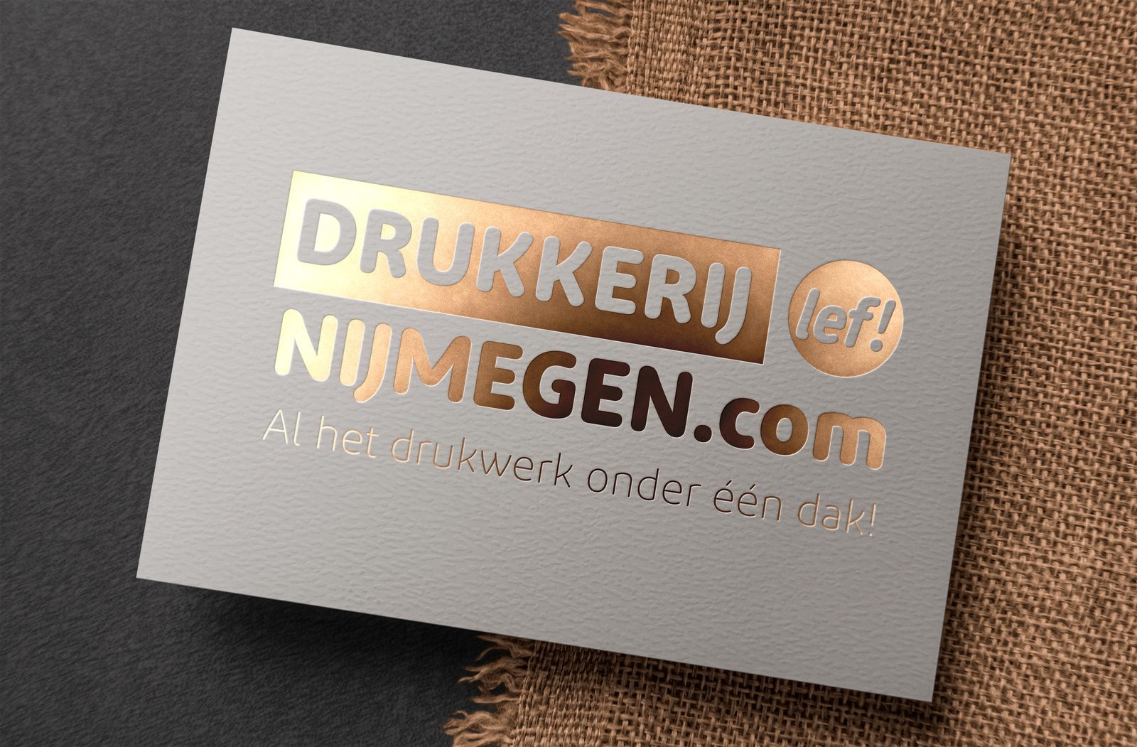 Grijs papier met een logo in goudfolie op een jute ondergrond
