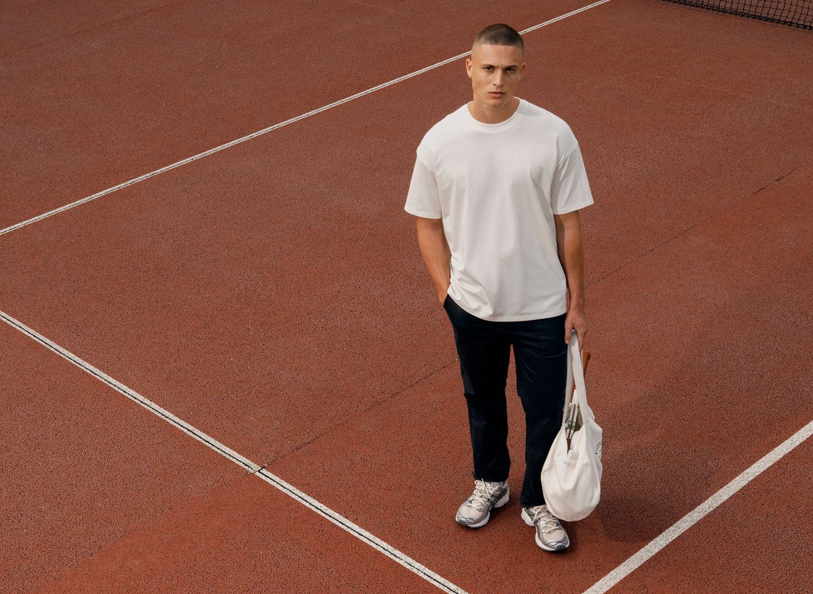Man in een wit oversized T-shirt op een gravelbaan