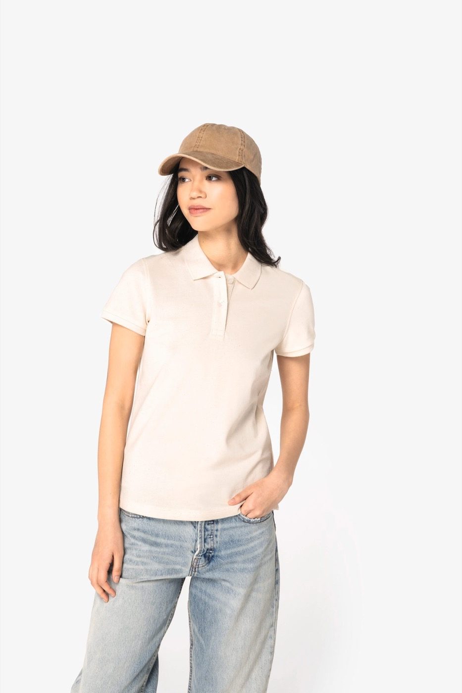 Vrouw in een ecru polo met pet en spijkerbroek
