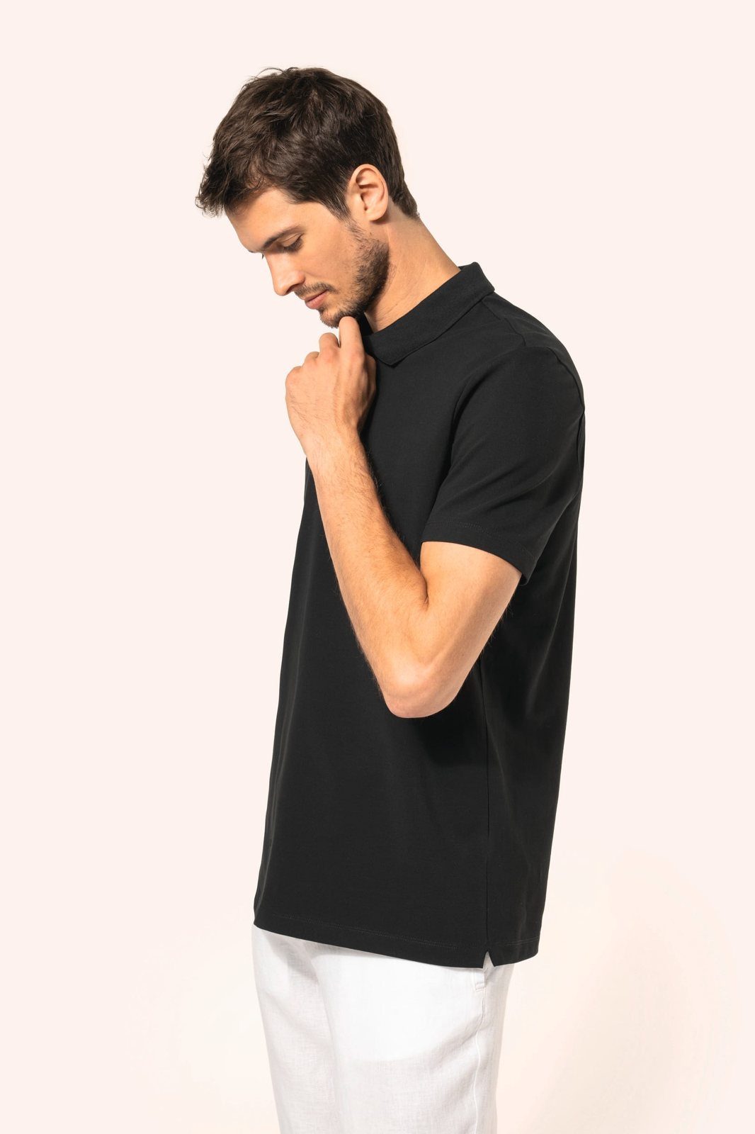Man in a black polo shirt with short sleeves and white trousers