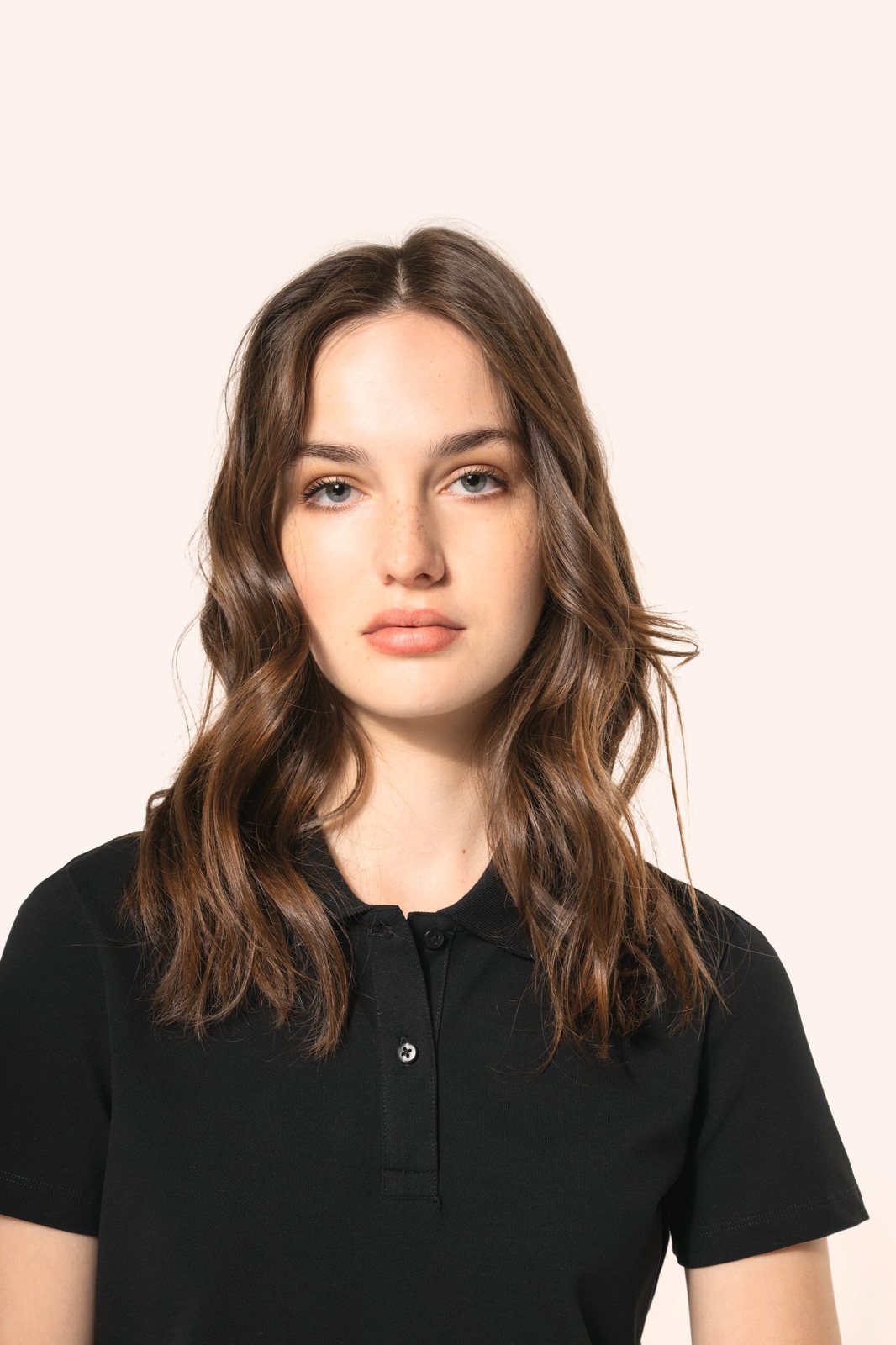 Woman with long brown hair in a black polo shirt