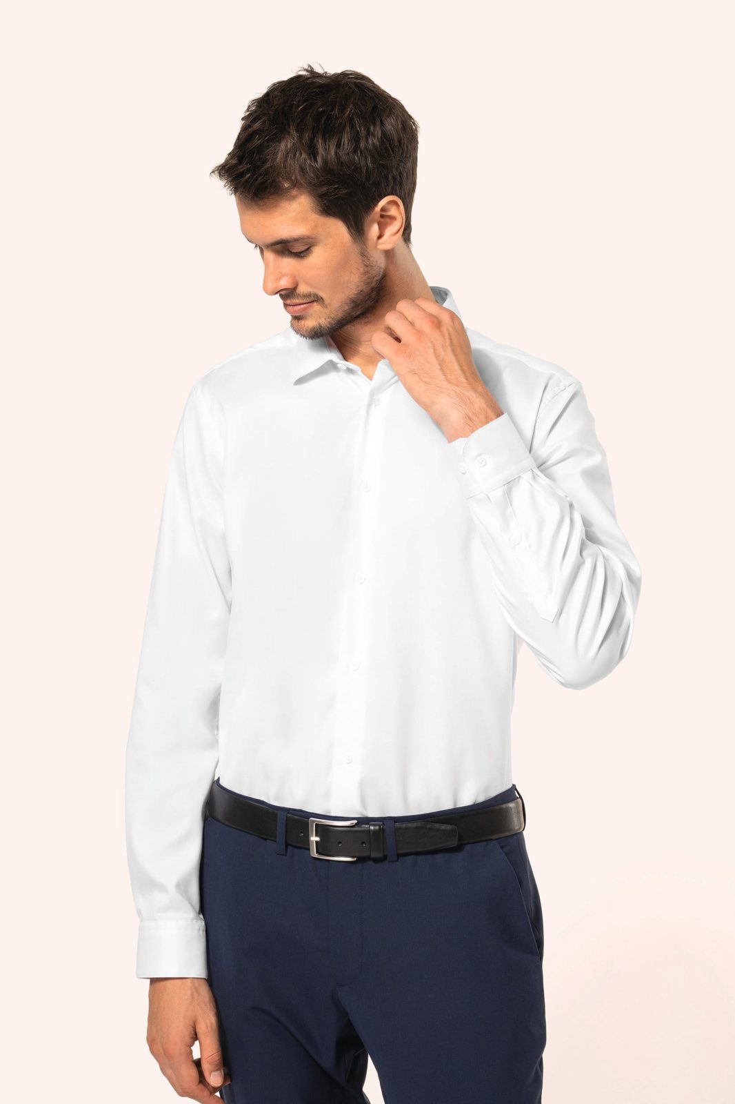 Man in a white shirt and dark blue trousers looking down