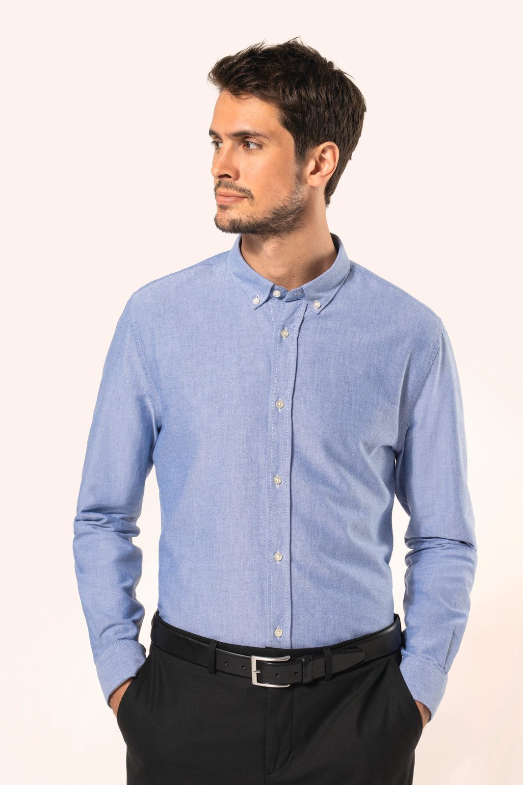Man in a light blue Oxford shirt with black trousers