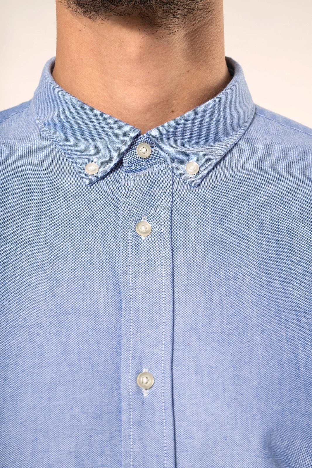 Close-up of the button-down collar of a blue Oxford shirt