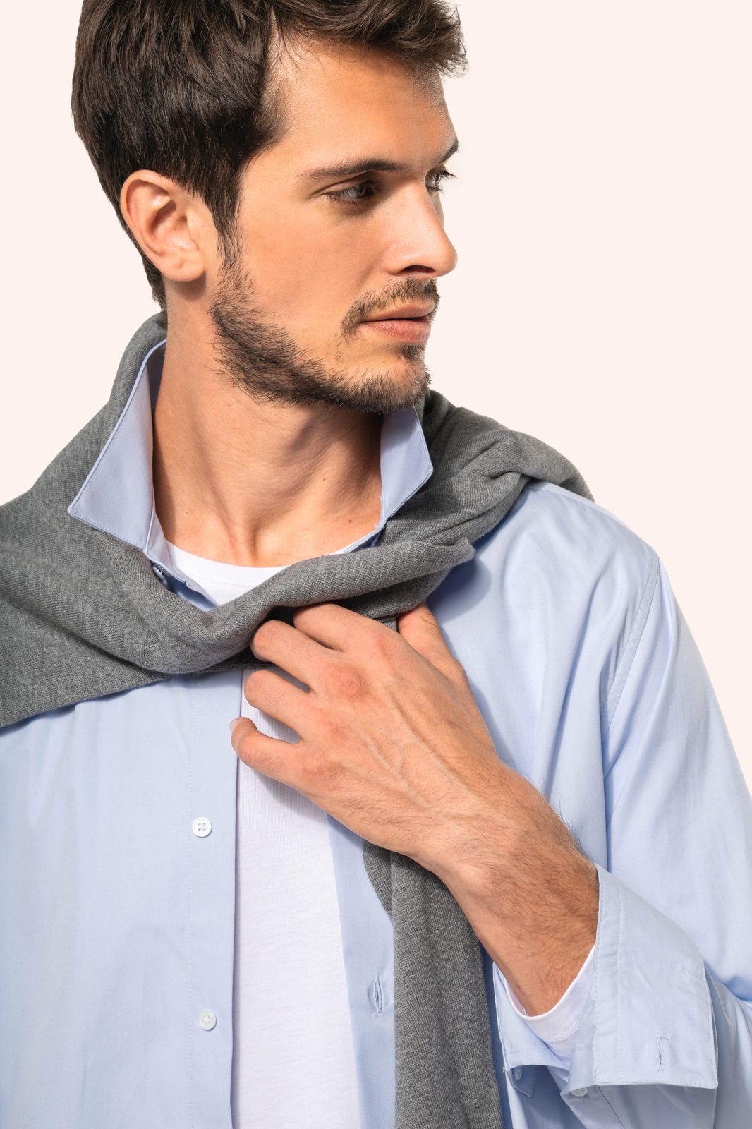 Man in a light blue shirt with a grey jumper over the shoulders