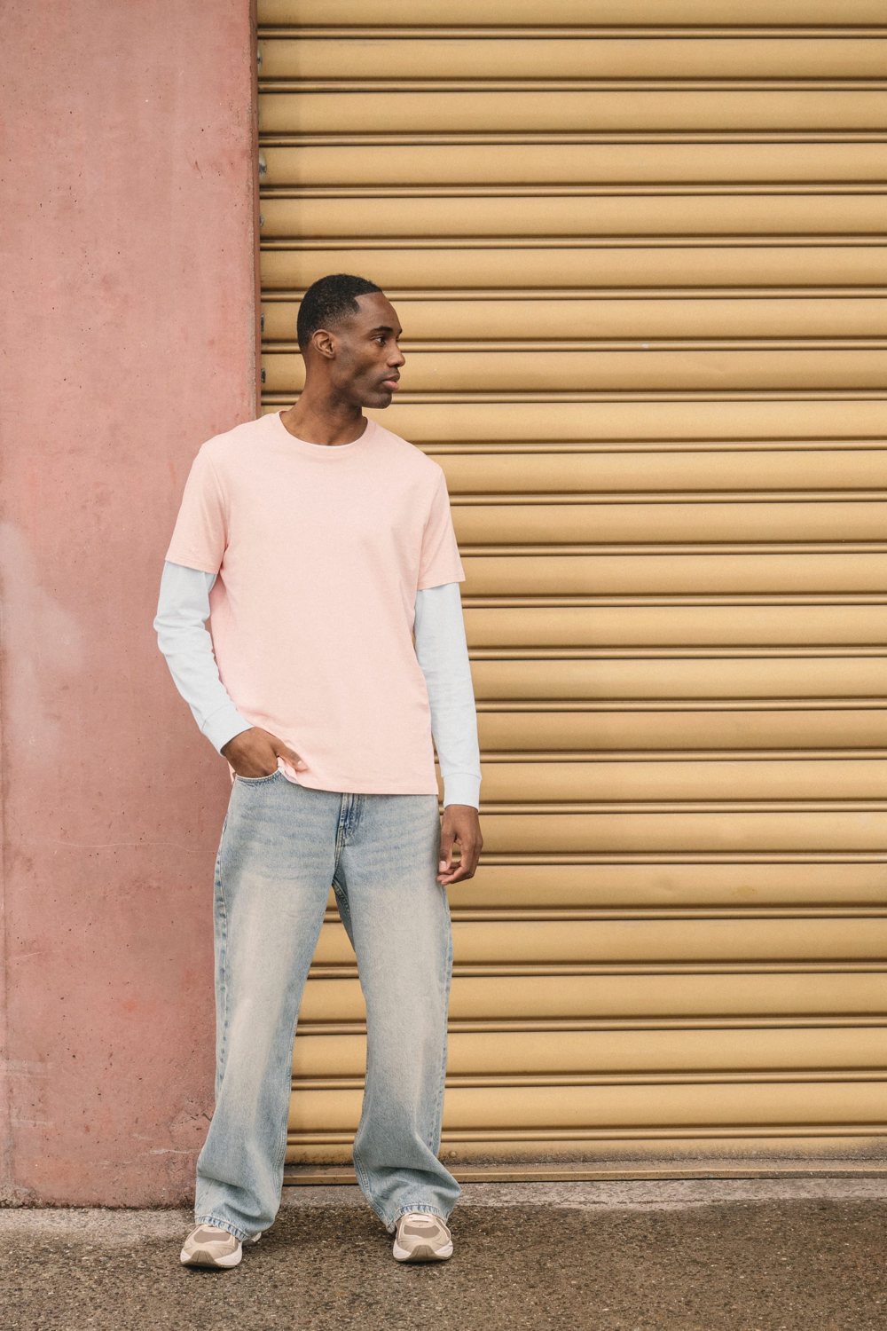 Man in een roze T-shirt voor een roldeur