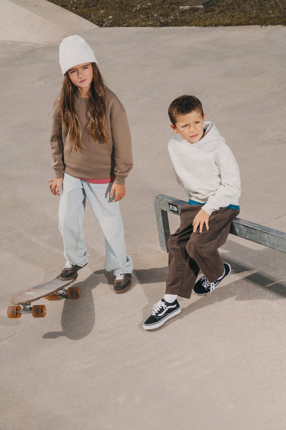 Twee kinderen in duurzame sweaters bij een skatebaan
