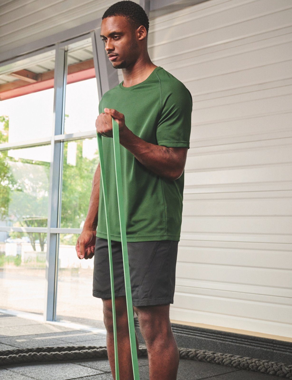 Man traint met een weerstandsband in een groen Proact-shirt