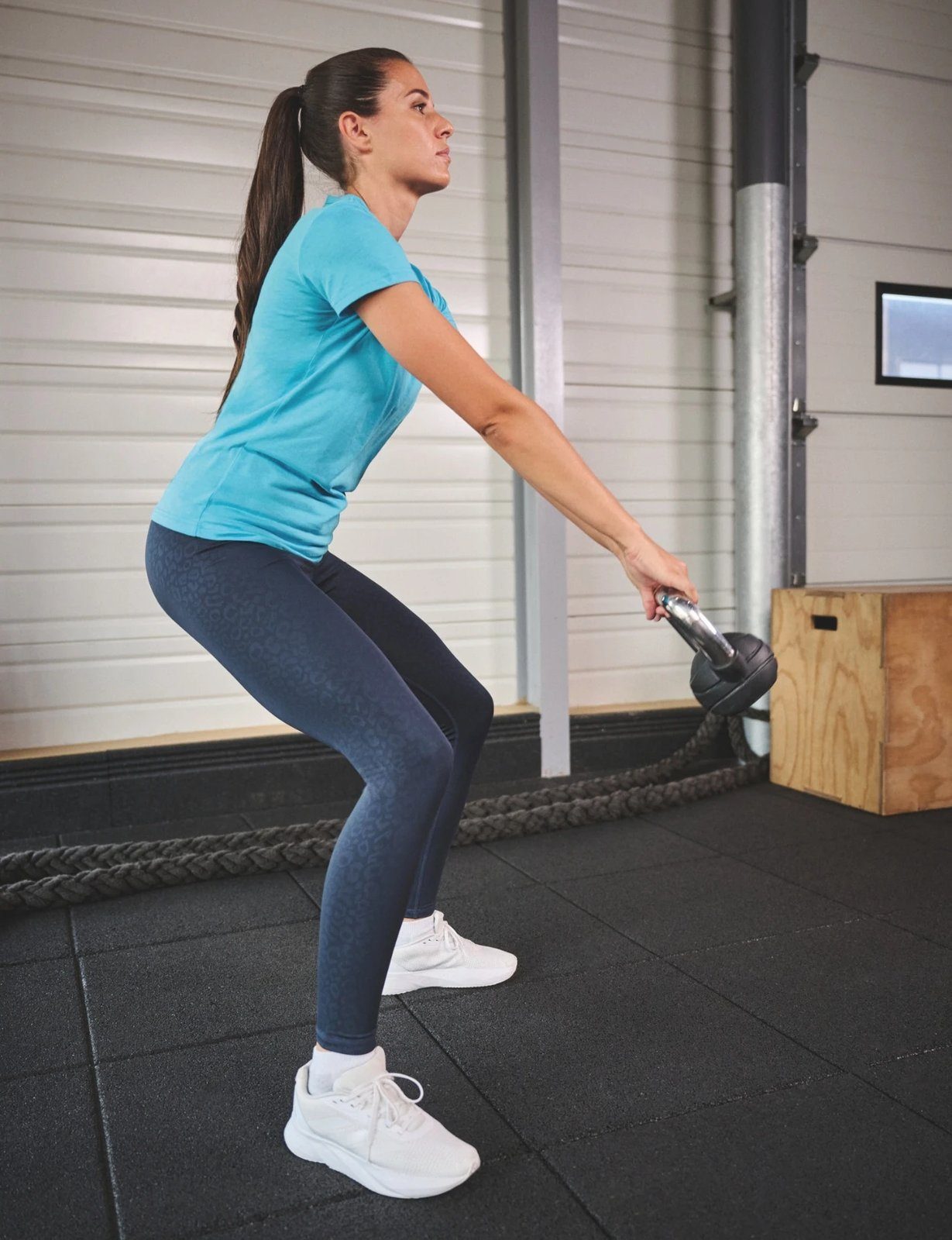 Vrouw traint met een kettlebell in een Proact-sportshirt