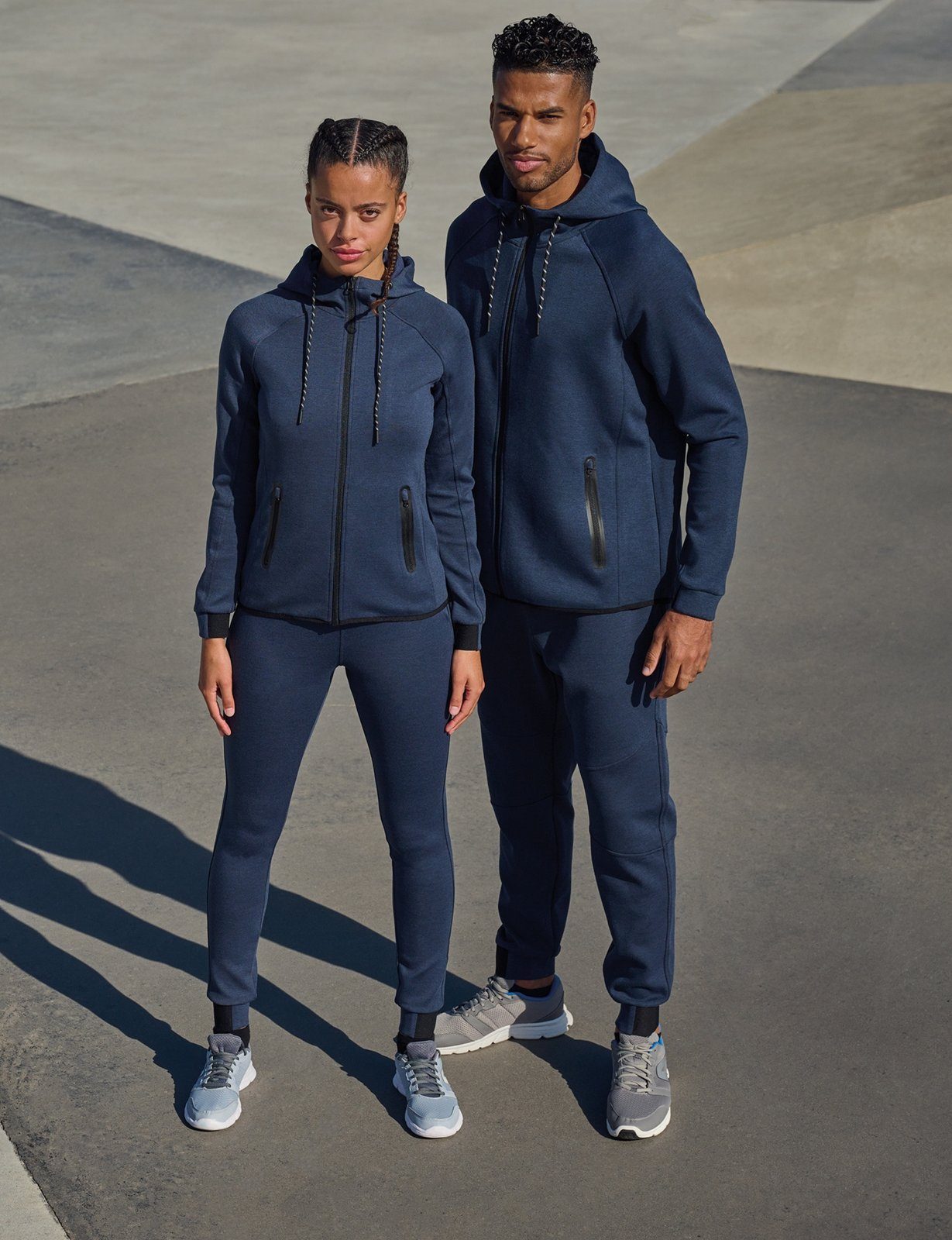 Een man en een vrouw in een navy Proact-trainingspak op een betonnen trap