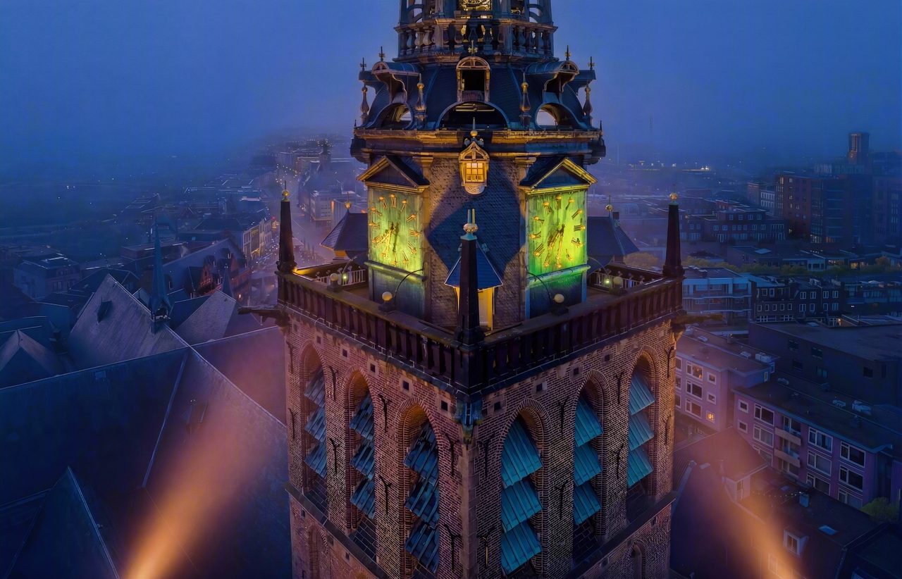 De verlichte toren van de Stevenskerk in het centrum van Nijmegen bij avond, van bovenaf